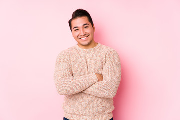 Young curvy man posing in a pink background isolated laughing and having fun.
