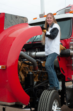 Woman truck driver doing a pre-trip inspection on a big truck