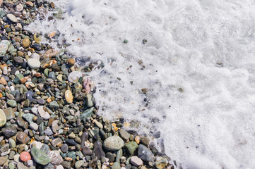 pebble coastline. Seashore with transparent water and small stones.