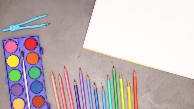 Colorful school, office and art supplies appear on grey background - Stop motion 