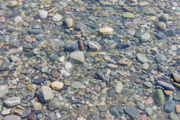 pebble coastline. Seashore with transparent water and small stones.