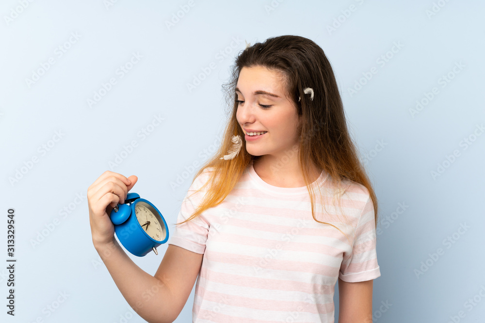 Wall mural young brunette girl holding vintage clock over isolated background