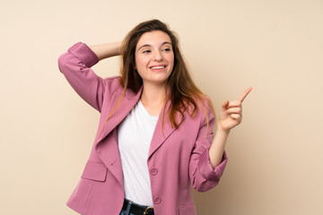 Young brunette girl with blazer over isolated background surprised and pointing finger to the side