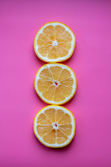 Flat lay composition with yellow lemons and space for text on color pink background.
