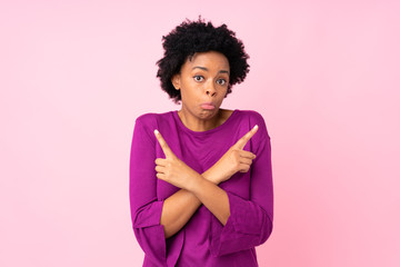 African american woman over isolated pink background pointing to the laterals having doubts