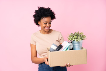 African american woman making a move while picking up a box full of things with happy expression
