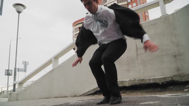 Parkour in a business suit. The guy is a businessman jumping at the top. Tracer office worker. Slow motion.