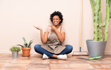 Gardener woman sitting on the floor holding copyspace imaginary on the palm to insert an ad