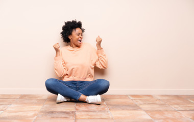 African american woman sitting on the floor celebrating a victory