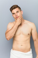 Fototapeta premium Young caucasian man shirtless touching his chin.