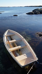 Little wooden boat floating on shallow water on a sunny day