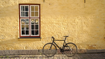 Fototapeta na wymiar Bicycle leaning against yellow brick hipster shop