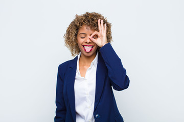 young woman african american smiling happily with funny face, joking and looking through peephole,...
