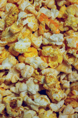 Yellow caramelized popcorn background, close up. Fast food, junk food. Abstract colorful food background.