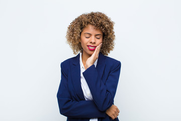 young woman african american holding cheek and suffering painful toothache, feeling ill, miserable...