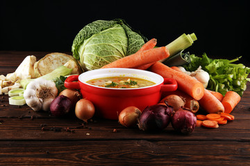 Broth with noodles and carrots, various fresh vegetables in a pot - colorful fresh clear spring...