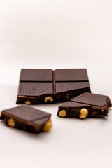 Dark chocolate pieces with whole hazelnuts isolated on white background