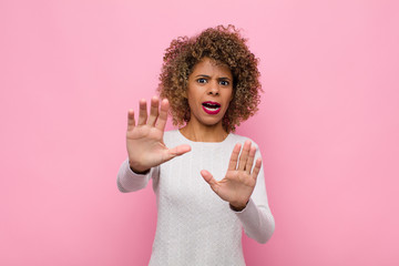 young african american woman feeling terrified, backing off and screaming in horror and panic,...