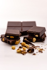 Dark chocolate pieces with whole hazelnuts isolated on white background
