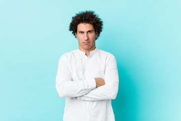 Young curly mature man wearing an elegant shirt unhappy looking in camera with sarcastic expression.