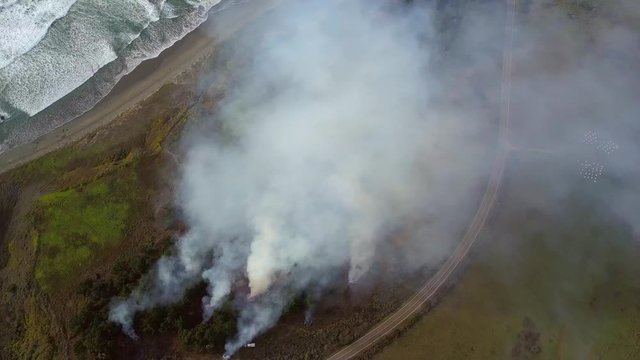 Aerial, drone shot overlooking firetrucks fighting wildfires, on a cloudy day, in Big sur, California, USA