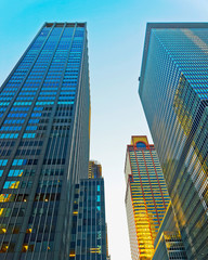 Fototapeta premium Bottom up Street view on Financial District of Lower Manhattan, New York City, NYC, USA. Skyscrapers tall glass buildings United States of America. Blue sky on background. Empty place for copy space.