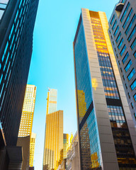Fototapeta na wymiar Bottom up Street view on Financial District of Lower Manhattan, New York City, NYC, USA. Skyscrapers tall glass buildings United States of America. Blue sky on background. Empty place for copy space.