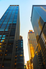 Fototapeta premium Bottom up Street view on Financial District of Lower Manhattan, New York City, NYC, USA. Skyscrapers tall glass buildings United States of America. Blue sky on background. Empty place for copy space.