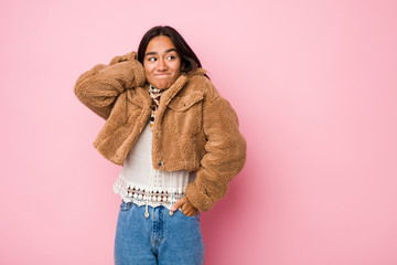 Young mixed race indian woman wearing a short sheepskin coattouching back of head, thinking and making a choice.