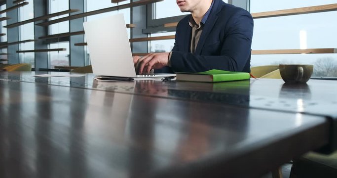 Concerned man working on laptop computer and looking away thinking solving problem at office. Serious athletic male working with notebook