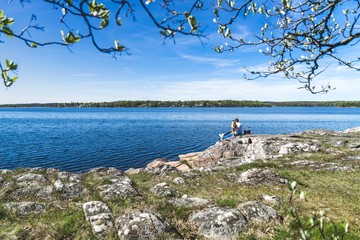 Young couple sitting beside the water with trees in the foreground. 