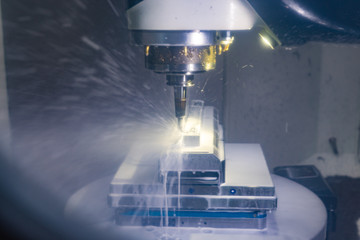 CNC Fräsmaschine beabreitet unter Zufuhr von einer Kühlschmierung / Kühlmittel einen Metallblock...