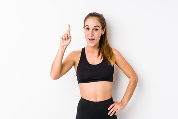 Young caucasian fitness woman posing in a white background having an idea, inspiration concept.