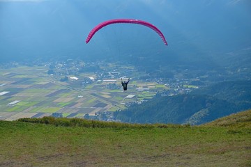 阿蘇の田園風景をバックに気持ちよさそうに飛ぶパラグライダー＠熊本