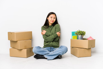 Young chinese woman moving to a new home hugs, smiling carefree and happy.