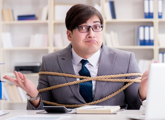 Businessman tied up with rope in office