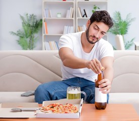 Man eating pizza having a takeaway at home relaxing resting