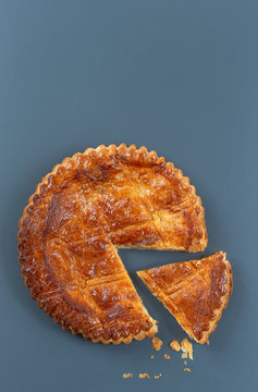 Epiphany Twelfth Night cake french galette des rois made of puff pastry, slice apart with the charm inside, top view grey background