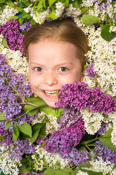 Happy little girl, a portrait of beautiful spring girl in flowering gardens, young charming elegant spring model, outdoor fashion photo of beautiful young preschool surrounded by flowers. The concept