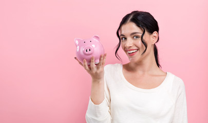 Young woman with a piggy bank on a pink background