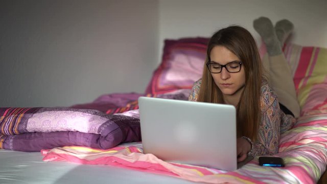 junge Frau arbeitet am Laptop auf dem Bett zuhause