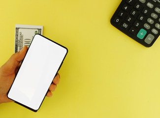 The white screen smartphone with a top $ 100 bank note and a yellow background calculator