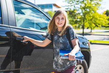 Happy teenage girl standing beside a car/suv getting dropped off/picked up from school.
