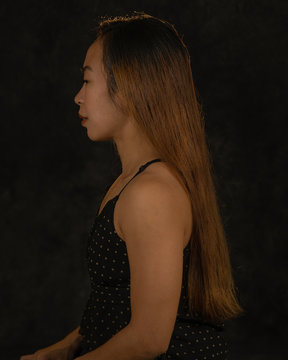 Beautiful young brunette Filipina woman posing in studio on dark background