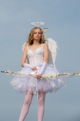 Charming curly little girl in white dress and wings - angel cupid girl. Child with angelic...