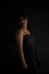 Fashion portrait of an young and attractive Indian Bengali brunette girl with black western dress in front of a black studio background. Indian fashion portrait and lifestyle.