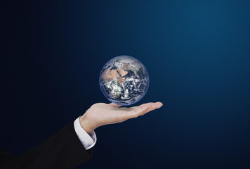 Businessman holding globe, on blue background. Global business concept. Element of this image are furnished by NASA