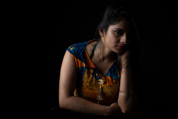 Obraz na płótnie Canvas Close up fashion portrait of an young and attractive Indian Bengali brunette girl with colorful western dress in front of a black studio copy space background. Indian fashion portrait and lifestyle.