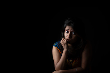 Close up fashion portrait of an young and attractive Indian Bengali brunette girl with colorful western dress in front of a black studio copy space background. Indian fashion portrait and lifestyle.