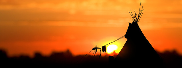 An American Indian tipi (teepee) against an evening sunset. - obrazy, fototapety, plakaty
